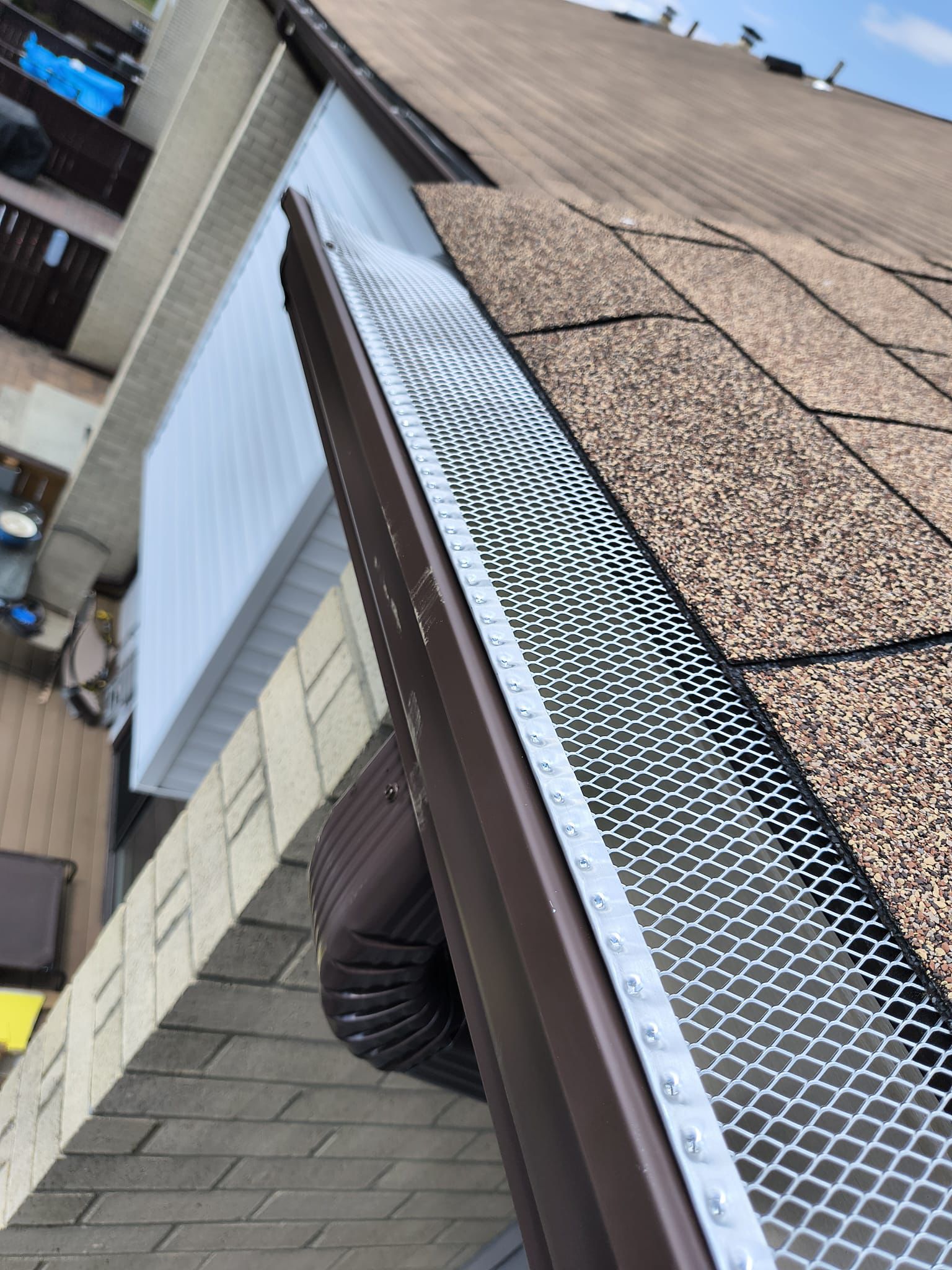 Brown seamless aluminum gutter with stainless mesh leaf guard on a NJ home