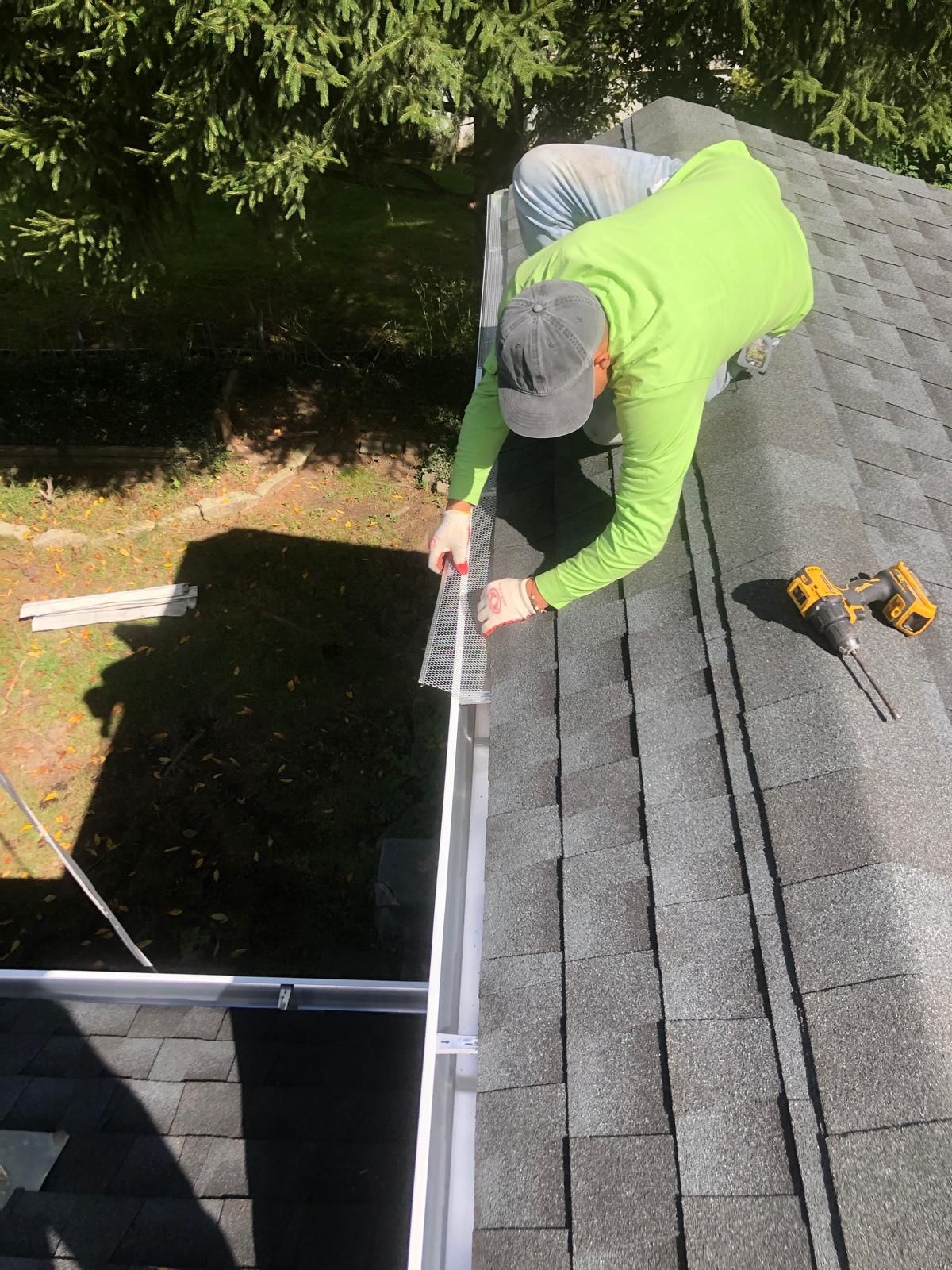 Installer fitting stainless mesh leaf-guard onto seamless gutter on a Ridgewood Victorian home