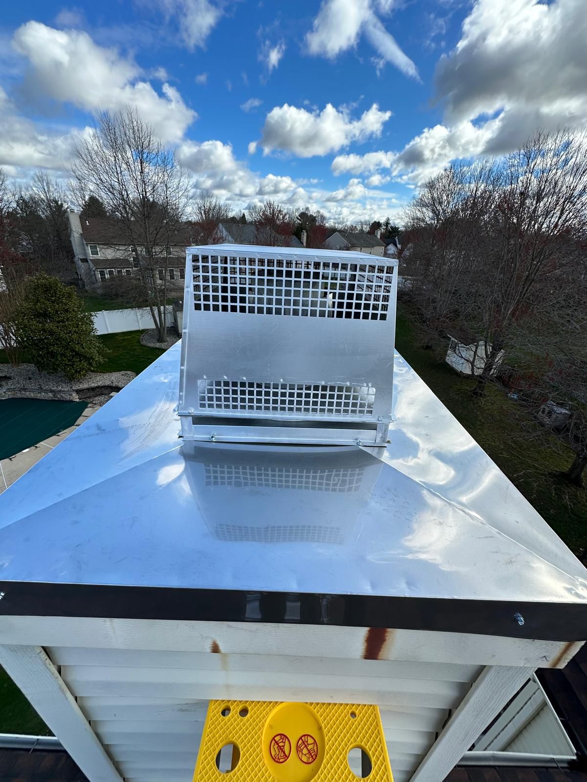 Stainless steel mesh chimney cap installed on a standing-seam topped chimney