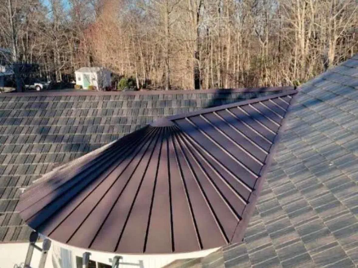 Custom brown standing-seam metal turret roof transitioning into shingle field