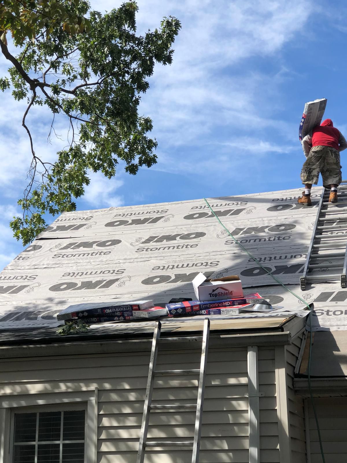GAF-certified roofer carrying Timberline shingle bundles up to a Northern NJ roof during installation