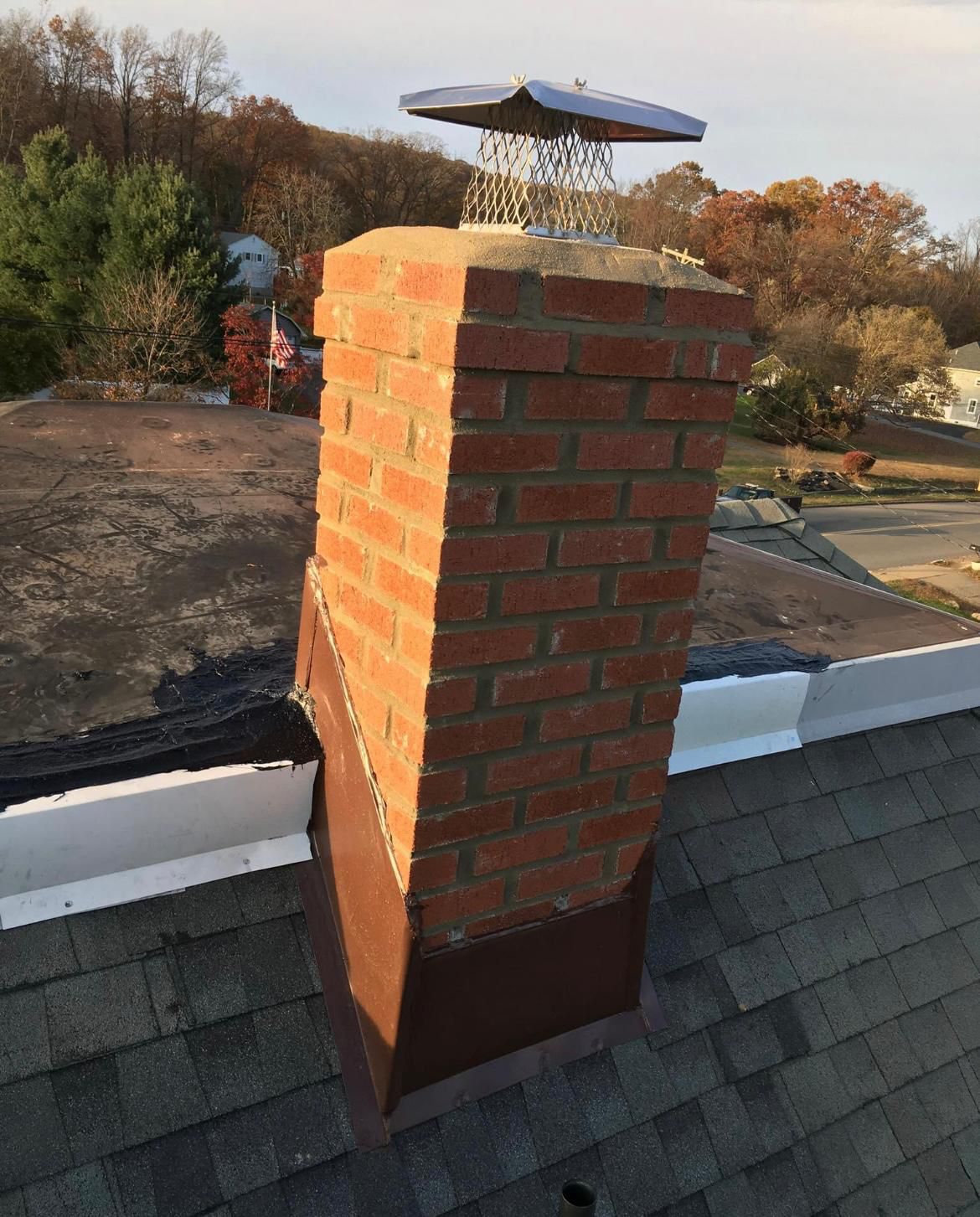 Brick chimney finished with stainless cap and copper-tone base flashing
