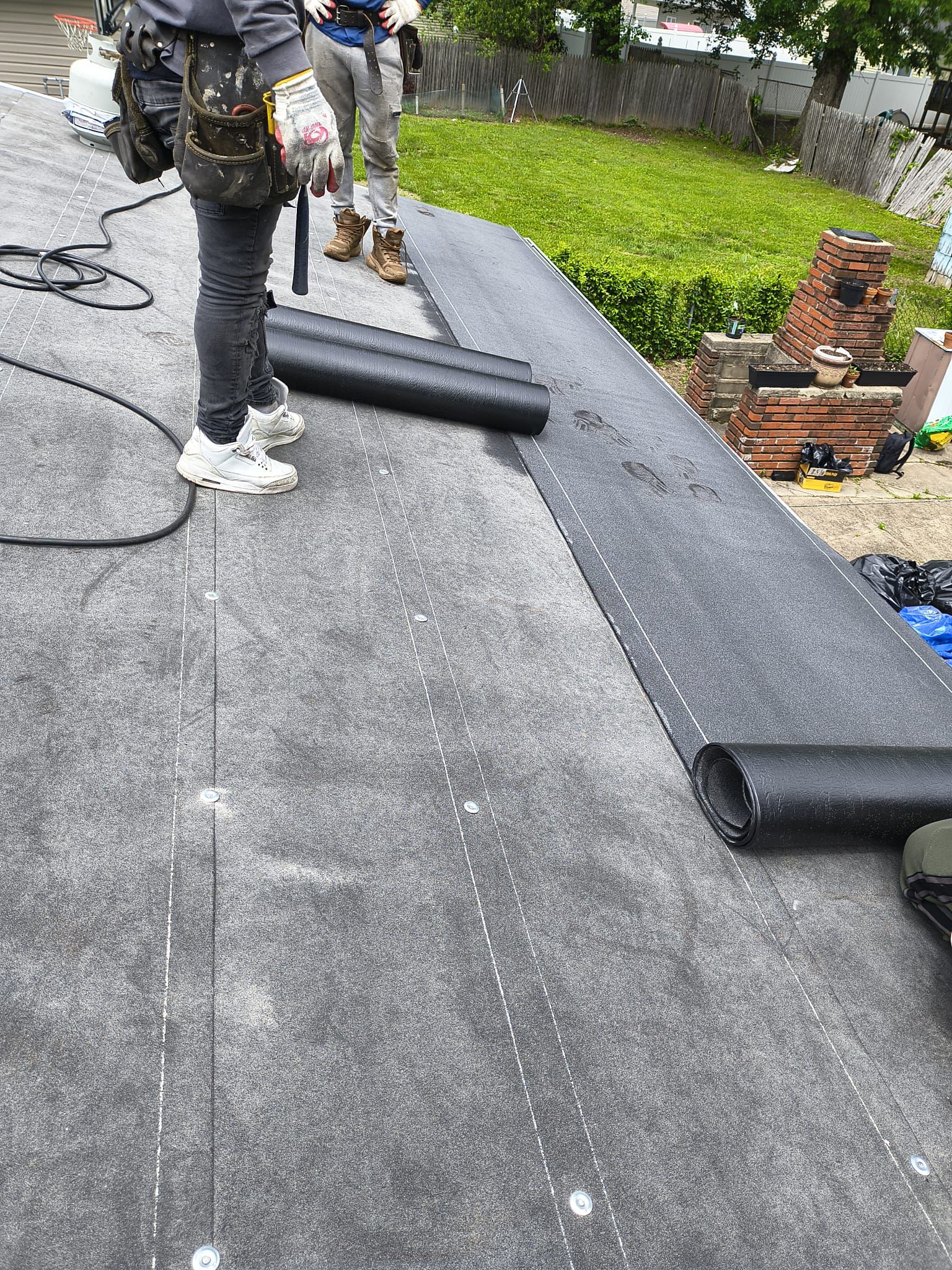 Roofing technician installing new EPDM membrane along a perimeter edge