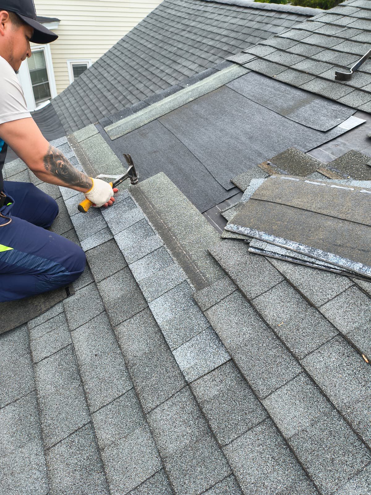 Roofing technician replacing damaged shingles on a Bloomfield-area home