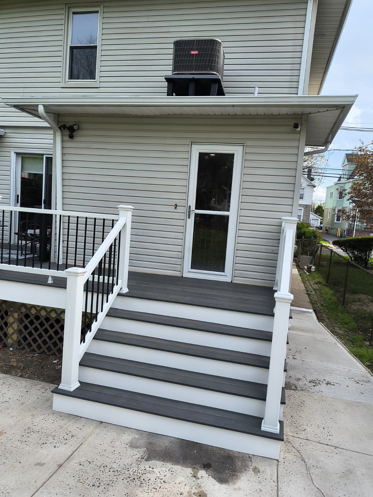 Two-tone composite deck with stairs and white railings on a backyard build