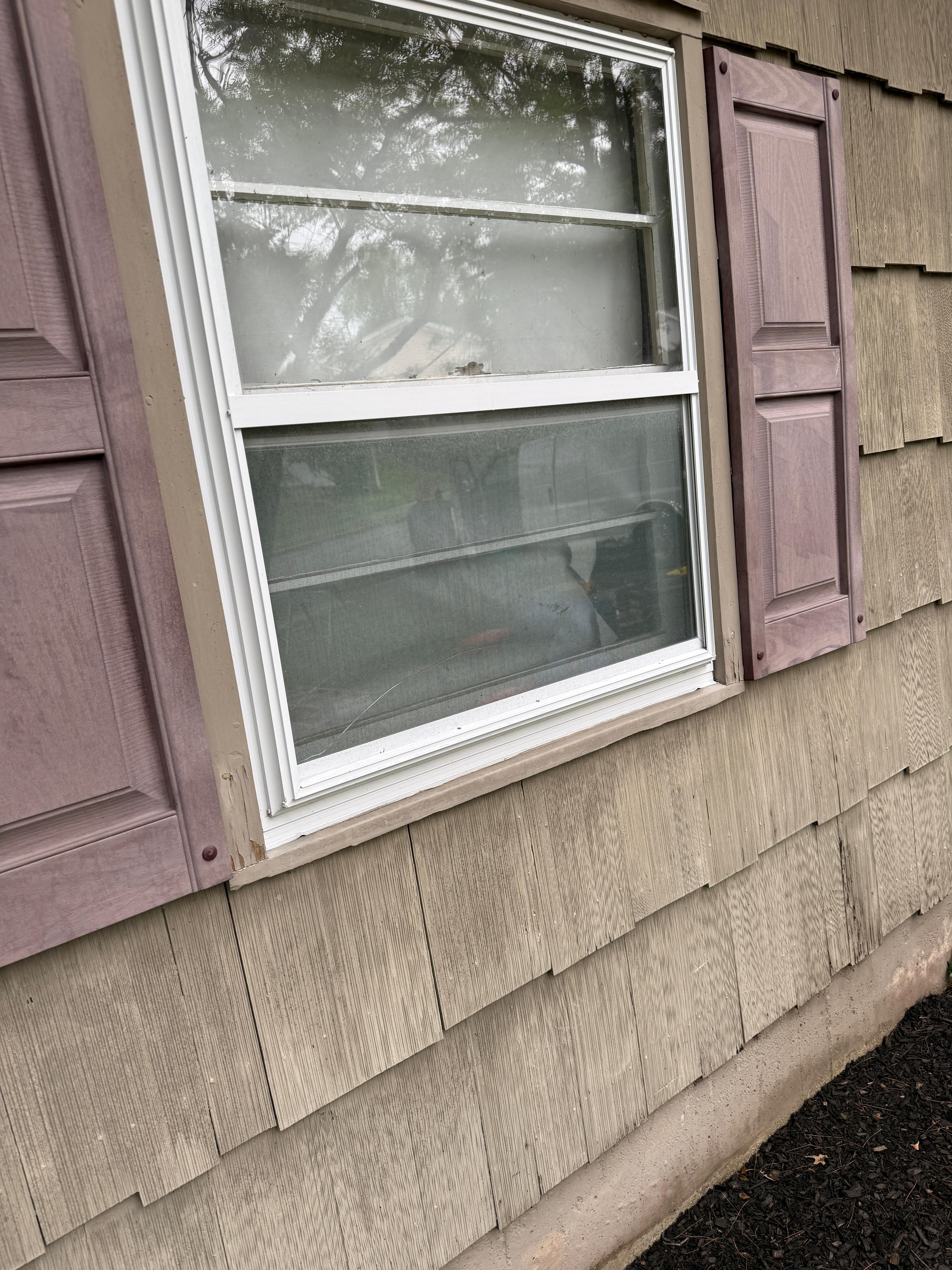 Close-up of failing shake and a mauve shutter at a second-floor window