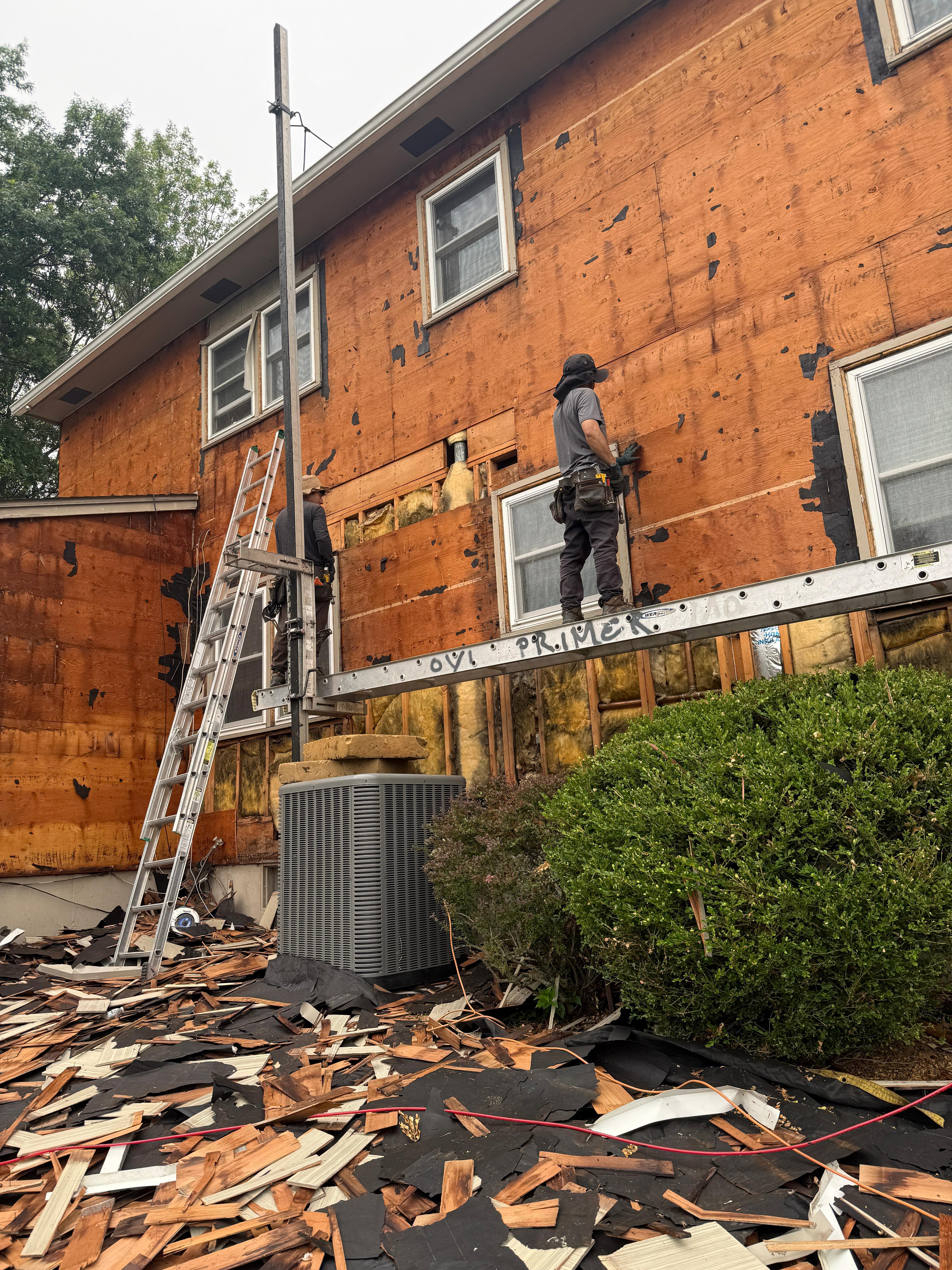 Full tear-off of the tall side elevation with debris tarped below