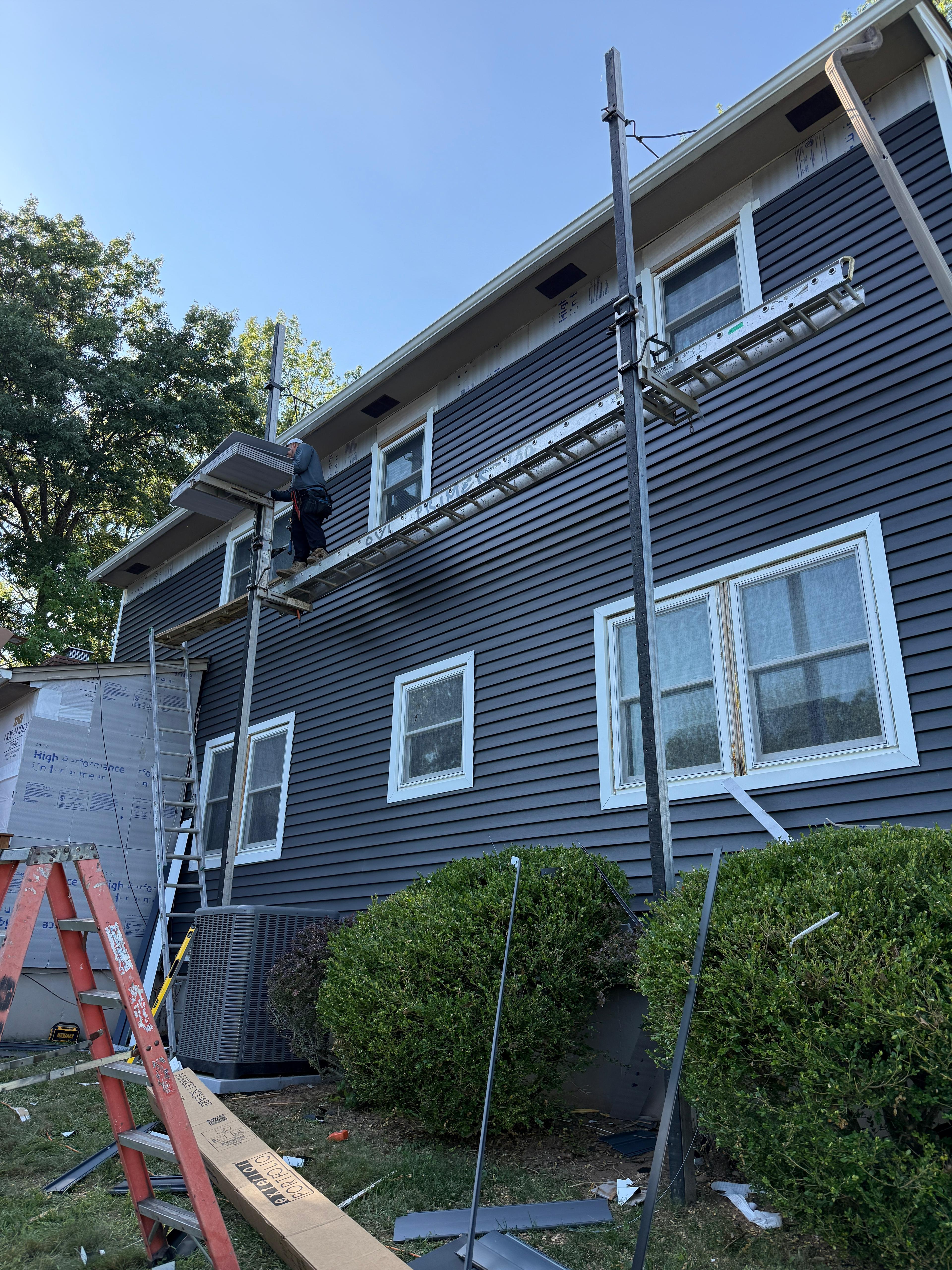 Soffit and fascia work underway above finished navy siding