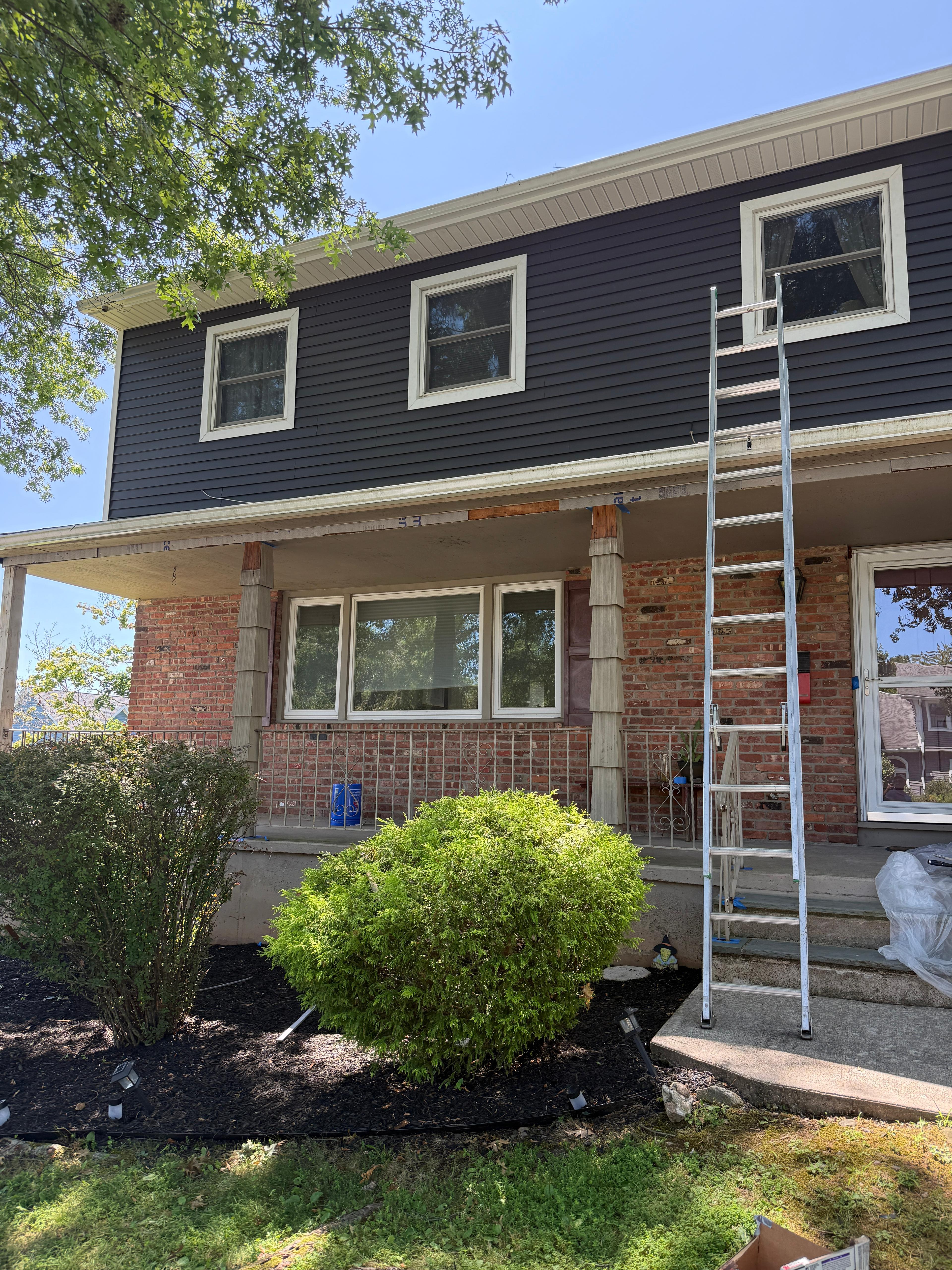 Front porch after residing, brick columns contrasting the navy cladding