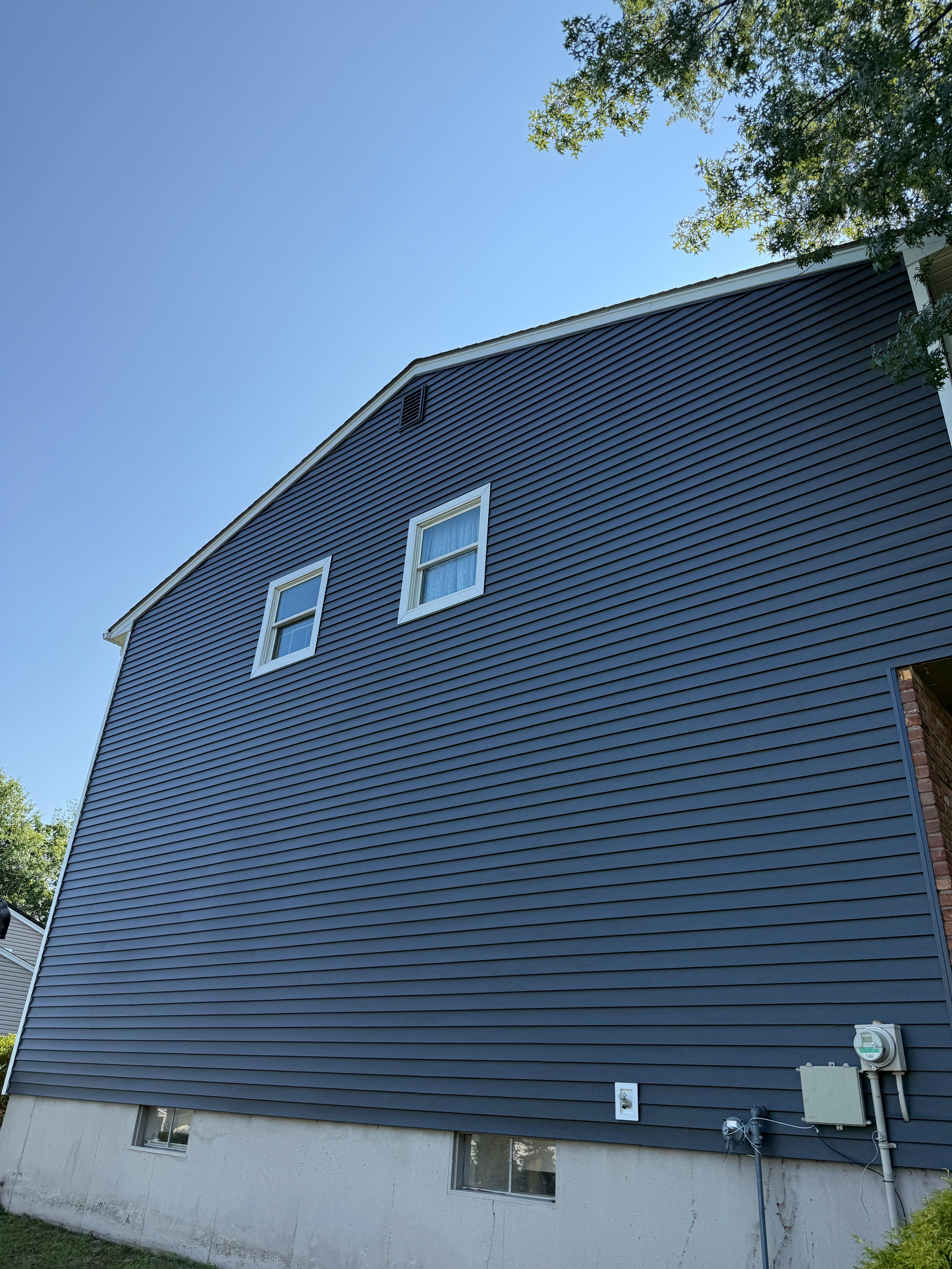 Completed gable wall in navy siding with white window trim