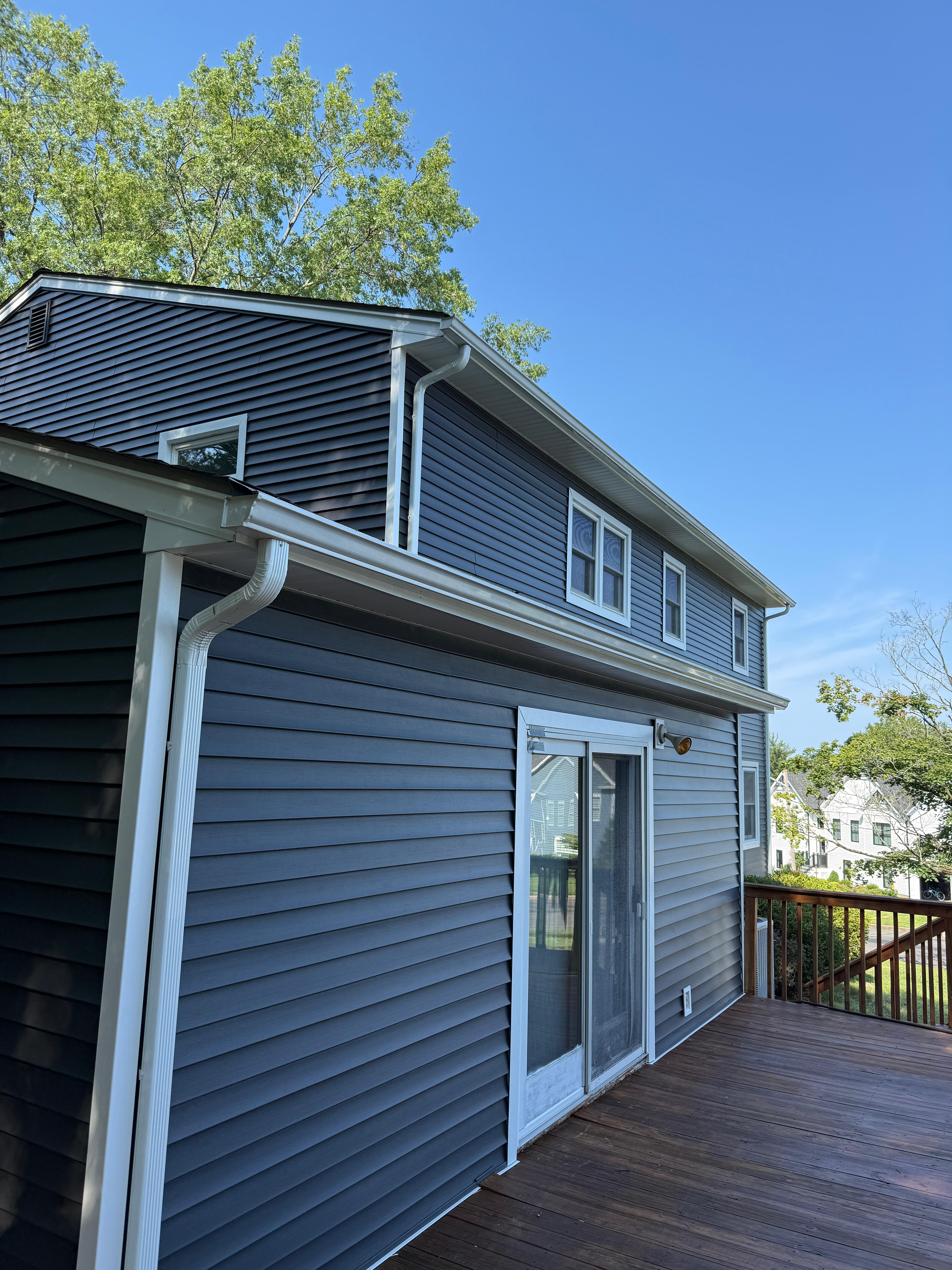 Rear deck elevation with navy siding, white trim and a sliding door