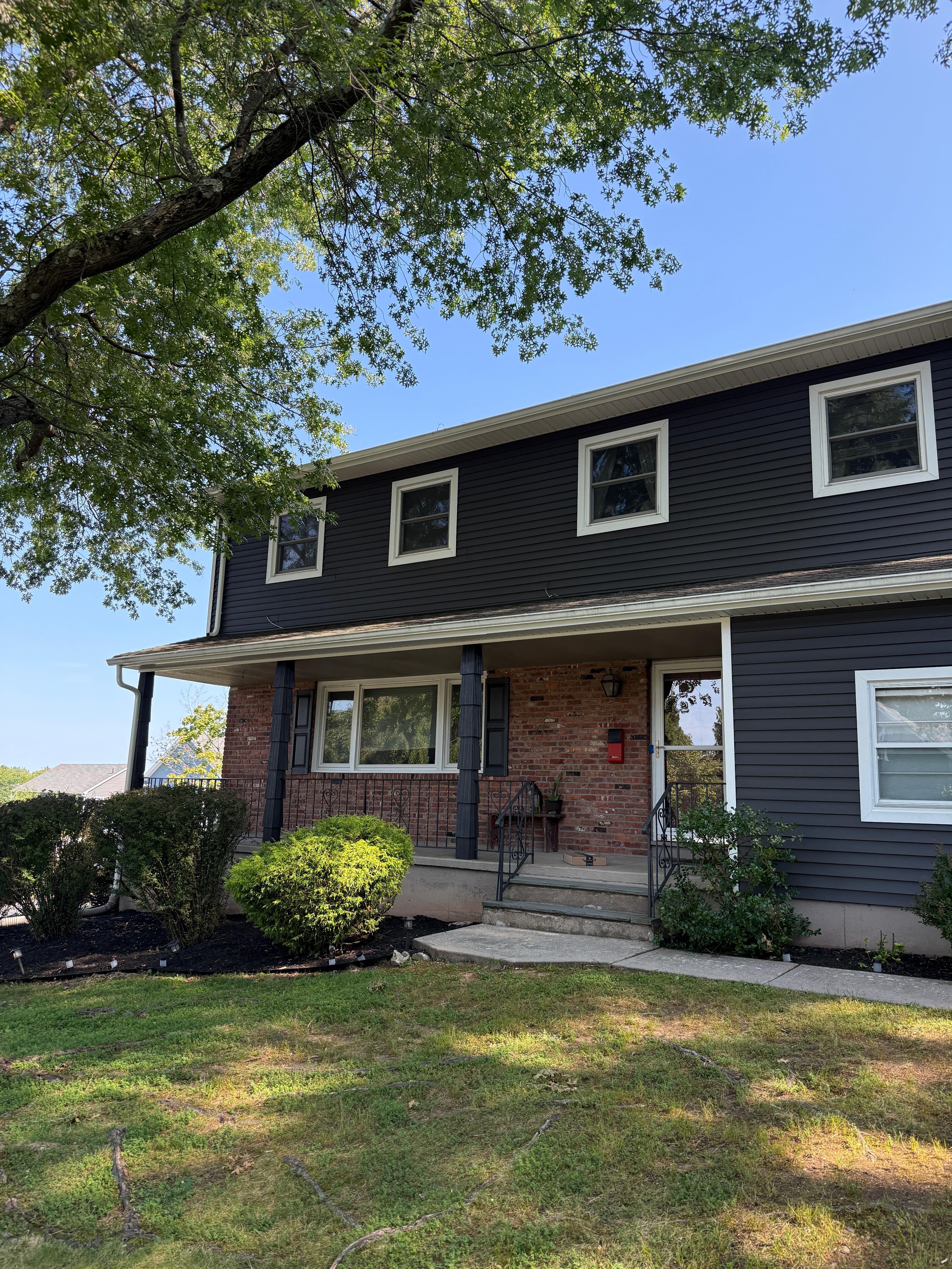 Front elevation after: home clad in deep navy vinyl siding with white trim