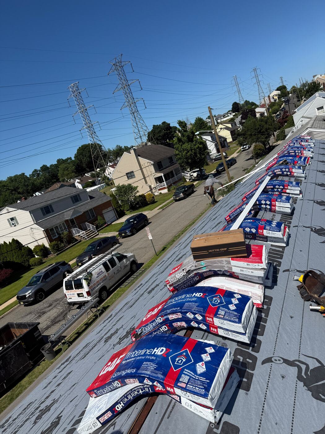 Shingle bundles and fastener boxes staged along the roof deck before installation