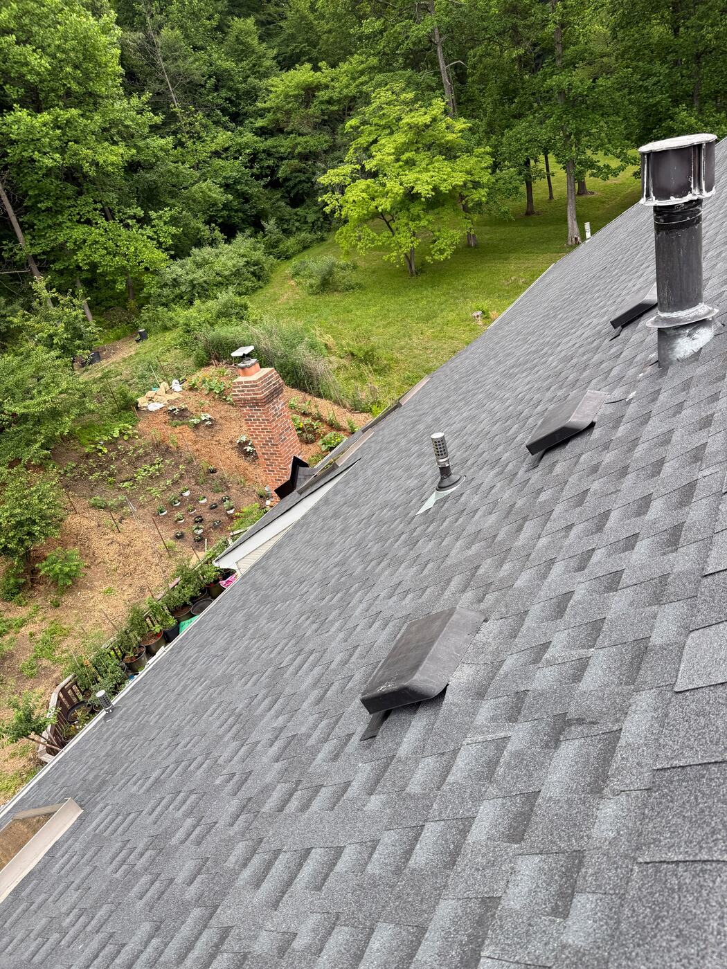 Newly flashed vent stacks and exhaust penetrations across a finished architectural shingle slope
