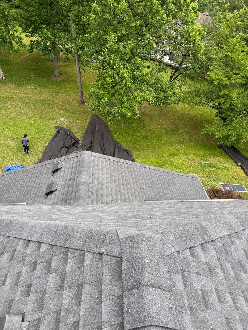 Ground tarps spread down the hillside below the eaves to collect tear-off debris